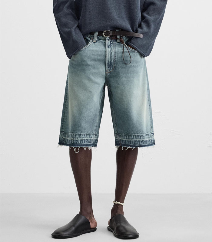 Baggy fit denim shorts made of cotton denim. Five pockets. Washed effect. Uneven hem. Front zip and button closure